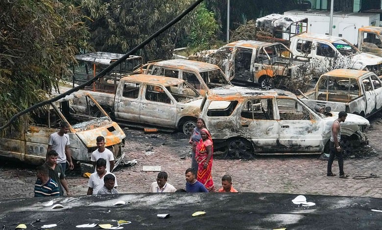 People walk past vandalized vehicles in the aftermath of anti-government protests