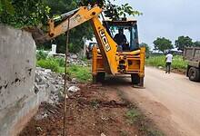 Boundary wall on a government land being demolished in Shamshabad