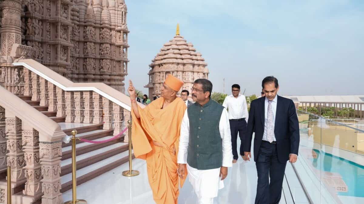 Union Minister Dharmendra Pradhan visits the intricately carved BAPS Hindu temple in Abu Dhabi, guided by a BAPS swami, with other officials walking alongside.