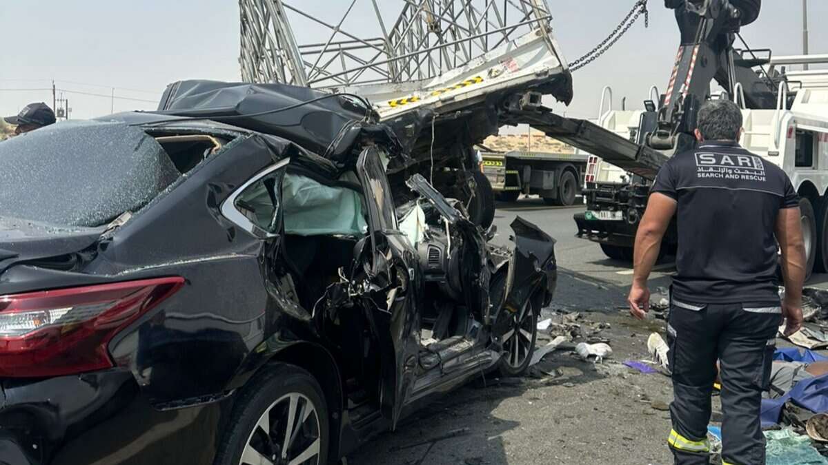 Damaged black car after accident with rescue team on highway, emergency response scene.