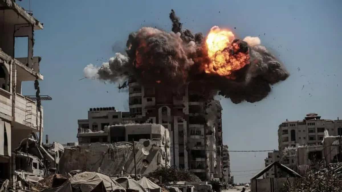 A large explosion and thick black smoke rise from a residential building in Gaza City during an Israeli air strike.