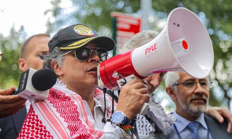 Colombian President Gustavo Petro speaks through a megaphone at a pro-Palestinian demonstration outside the United Nations headquarters, wearing a black cap and red-and-white keffiyeh.