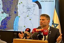 Bezalel Smotrich speaking at a press conference with a map of the West Bank behind him.