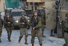 Israeli soldiers patrol near armoured vehicles at a West Bank checkpoint.