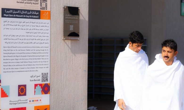 Pilgrims at Miqat Qarn Al-Manazil preparing to enter Ihram, with informational signage provided by the Royal Commission for Makkah City and Holy Sites.