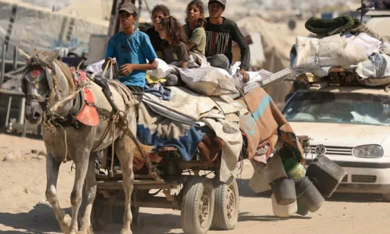 A group of Palestinians, including children, flee Gaza City on a horse-drawn cart loaded with belongings, alongside a car, amid an evacuation order.