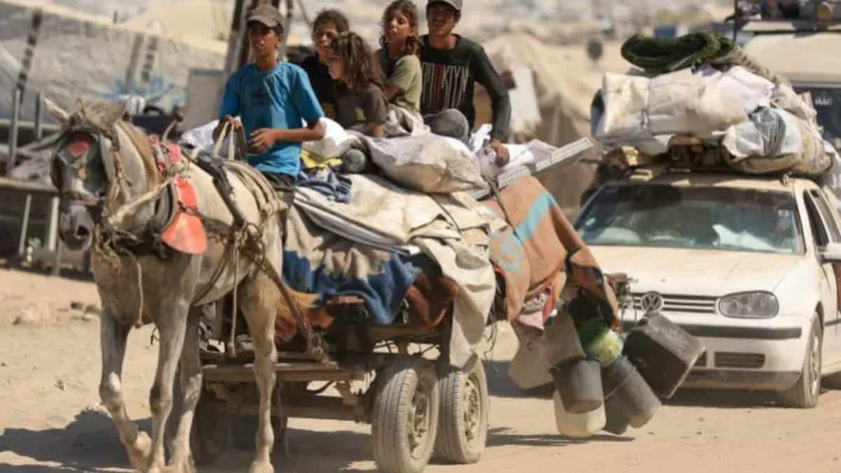 A group of Palestinians, including children, flee Gaza City on a horse-drawn cart loaded with belongings, alongside a car, amid an evacuation order.