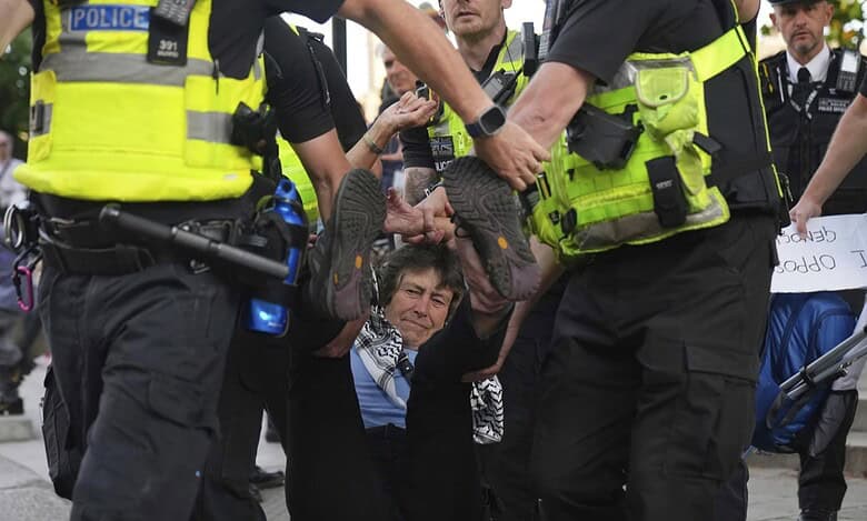 Police officers carry away a protester during a demonstration in London.