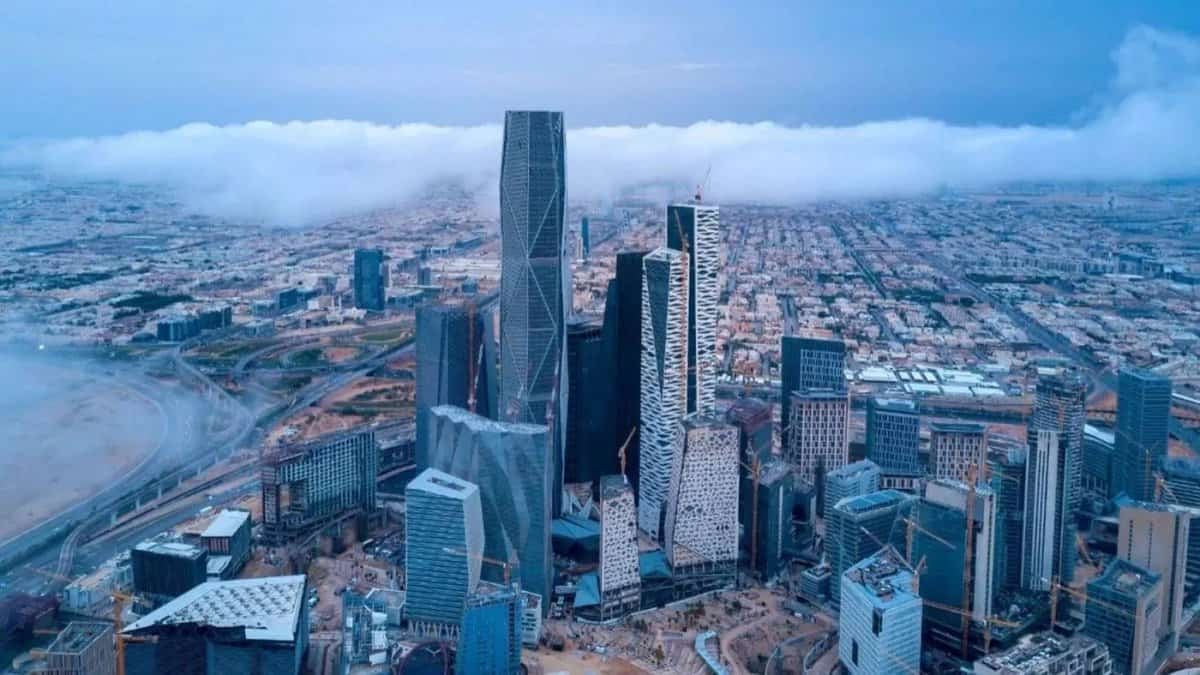 Aerial view of Riyadh city skyline with modern skyscrapers and surrounding urban landscape under cloudy sky.
