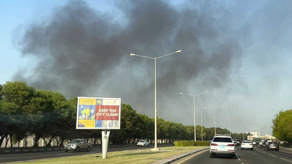 Black smoke rises above trees and a busy road in Doha following reported explosions.