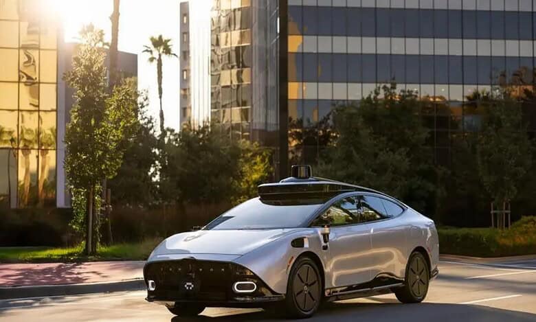 Sleek silver Tensor Robocar, a Level 4 autonomous vehicle, drives on a sunny Dubai street with lidar sensor, modern skyscrapers, and palm trees in the background.