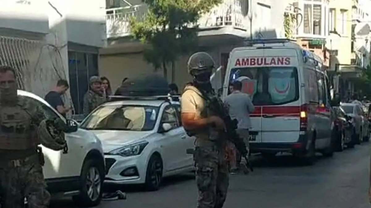 Turkish special forces guard a street in Izmir after a police station attack, with an ambulance in the background.
