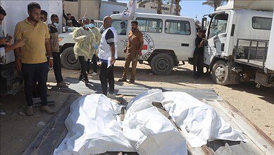 Bodies wrapped in white sheets lie on the ground as aid workers and officials stand nearby in Gaza, October 2022.