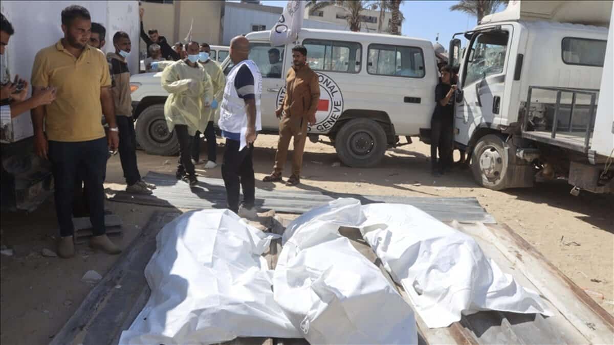 Bodies wrapped in white sheets lie on the ground as aid workers and officials stand nearby in Gaza, October 2022.