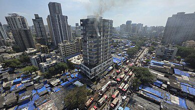 Smoke billows while firemen douse a fire breaking out at 13-storey commercial building JNS Business Center at Jogeshwari area in Mumbai on Thursday (PTI Photo)