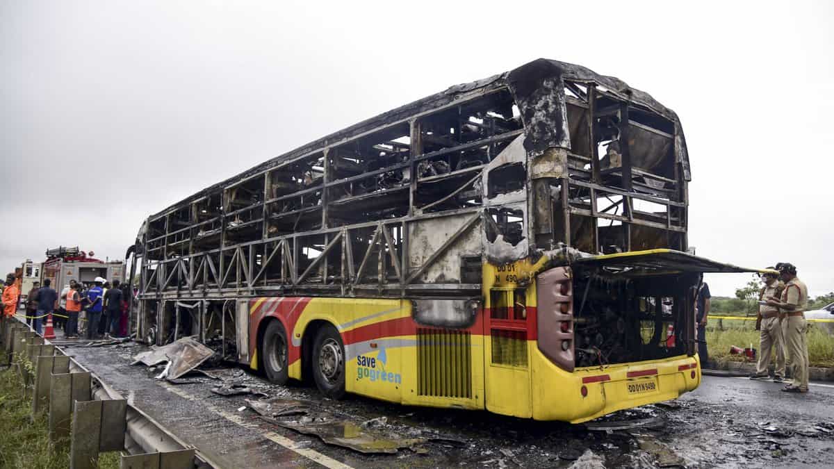 Police personnel investigate the spot where a Bengaluru-bound private bus caught fire after colliding with a two-wheeler, with the blaze being triggered after the motor bike with its fuel cap open was dragged underneath the bus, in Kurnool district on Friday. At least 20 people were killed in the accident. (PTI Photo)