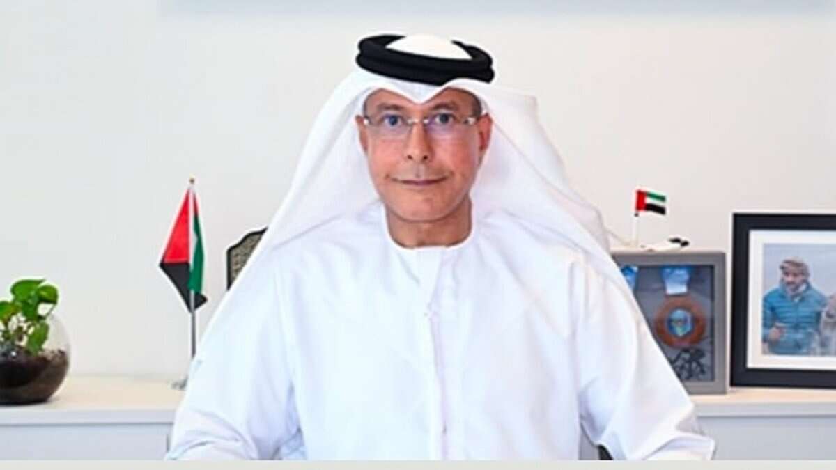 Emirati businessman and former diplomat Hamad bin Ahmed bin Salem Al Hajri seated at his desk with UAE flags and framed photo behind.