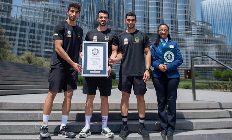 Dubai Civil Defence firefighters pose with Guinness World Record certificate in front of the Burj Khalifa.