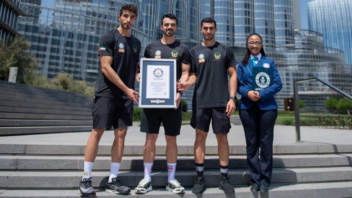 Dubai Civil Defence firefighters pose with Guinness World Record certificate in front of the Burj Khalifa.