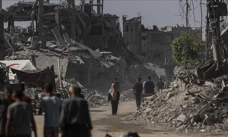 People walk through a street lined with destroyed buildings in a war-torn area.