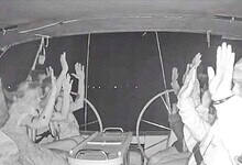 Global Sumud Flotilla activists raise their hands as Israeli forces intercept their boat at night.