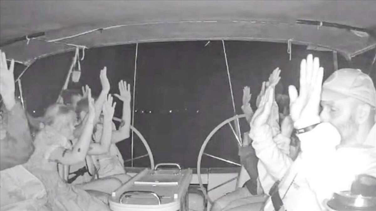 Global Sumud Flotilla activists raise their hands as Israeli forces intercept their boat at night.