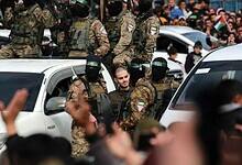 Hamas militants escort a captive during a public rally in Gaza.