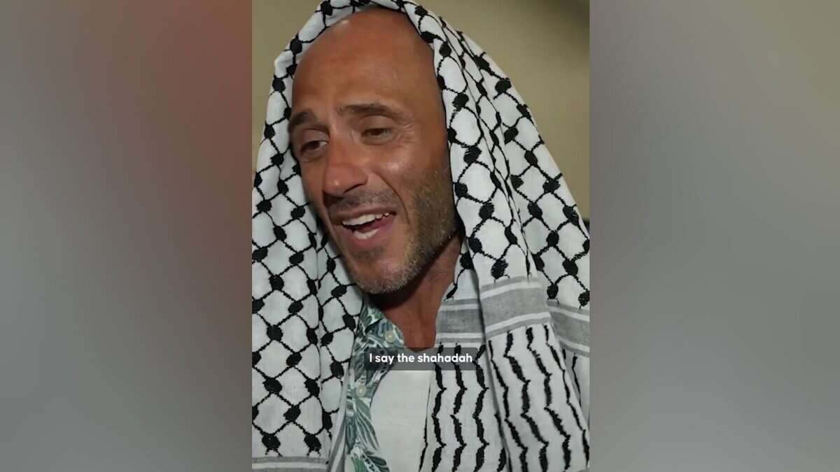 Italian activist wearing a black-and-white Palestinian keffiyeh speaks after embracing Islam.