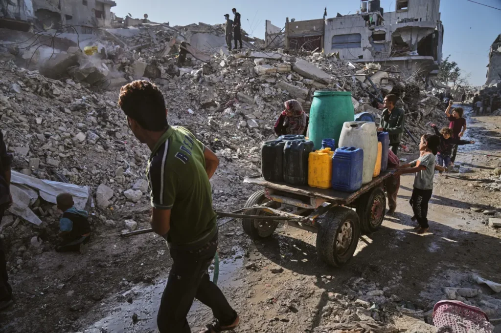 Palestinians collect and transport water through the rubble-strewn streets of Gaza City following heavy destruction.