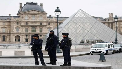Police officers stand guard outside the Louvre Museum near its glass pyramid in Paris following the crown jewels theft.