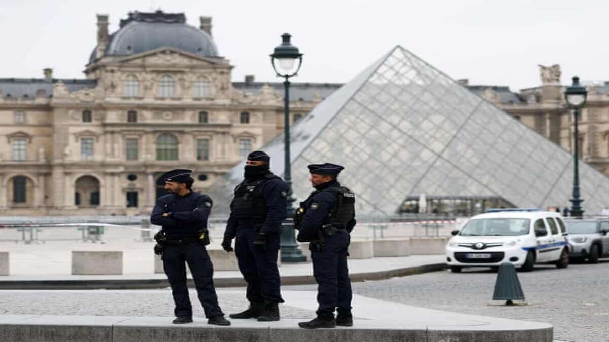 Police officers stand guard outside the Louvre Museum near its glass pyramid in Paris following the crown jewels theft.