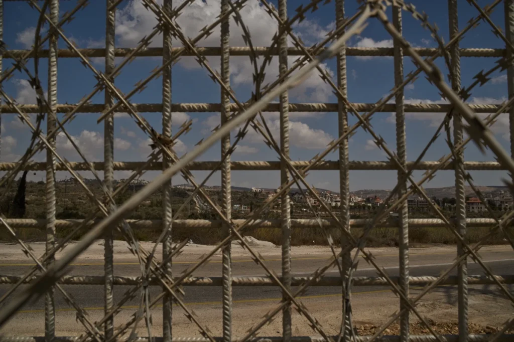 The West Bank village of Sinjil is seen through a fence built by Israeli authorities near Turmus Ayya during the Gaza war.