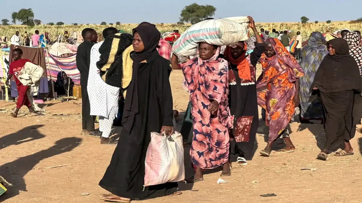 Displaced Sudanese civilians carry belongings through a camp in El Fasher.