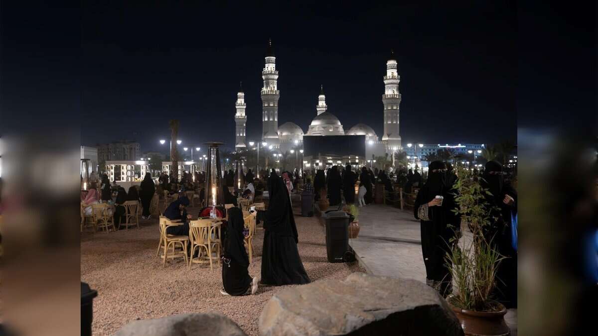 Night-time view of visitors and families at the outdoor promenade near Quba Mosque in Madinah city.