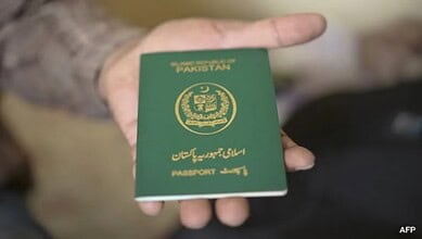 A person holding a Pakistani passport in their hand.