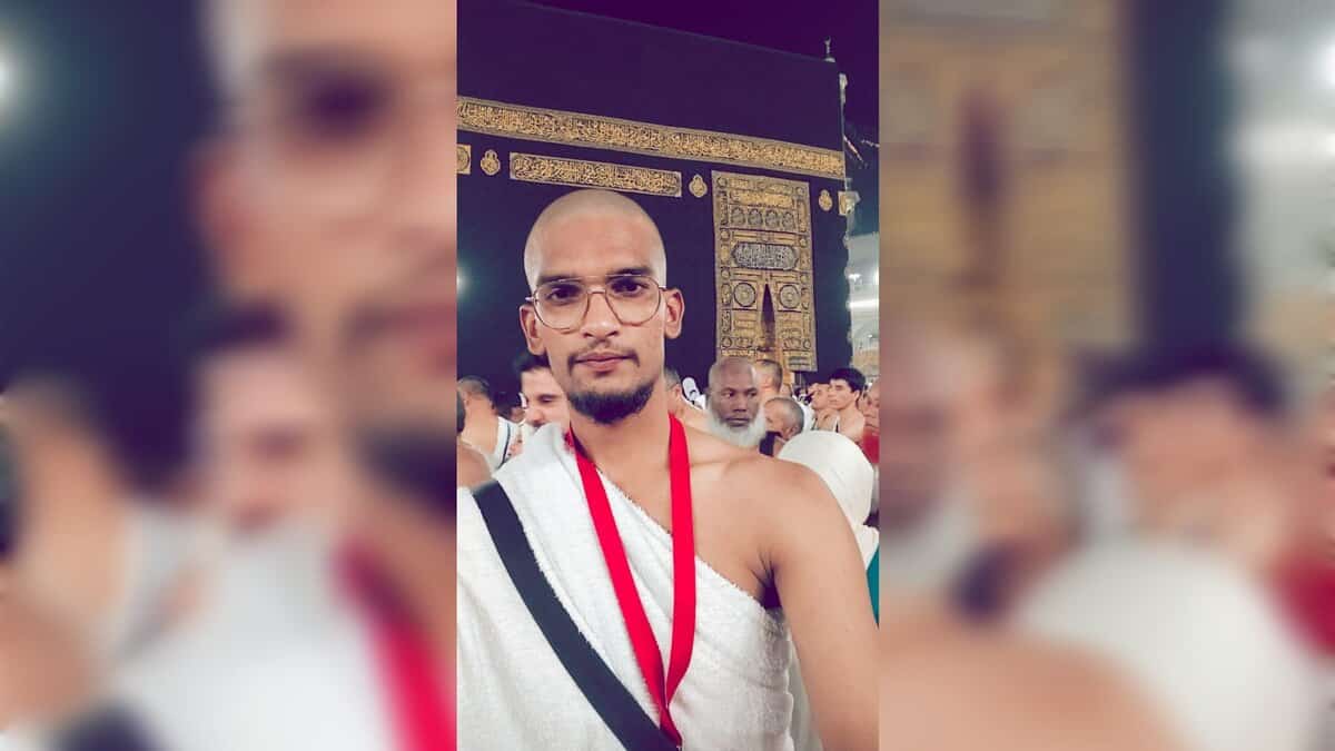 Abdul Shoeb Mohammed standing in front of the Kaaba during Umrah, wearing ihram and glasses, with pilgrims in the background.