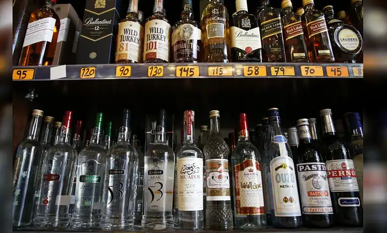 Shelves stocked with various alcoholic drinks, including Arabic arak, whiskies and spirits, arranged in a liquor store.