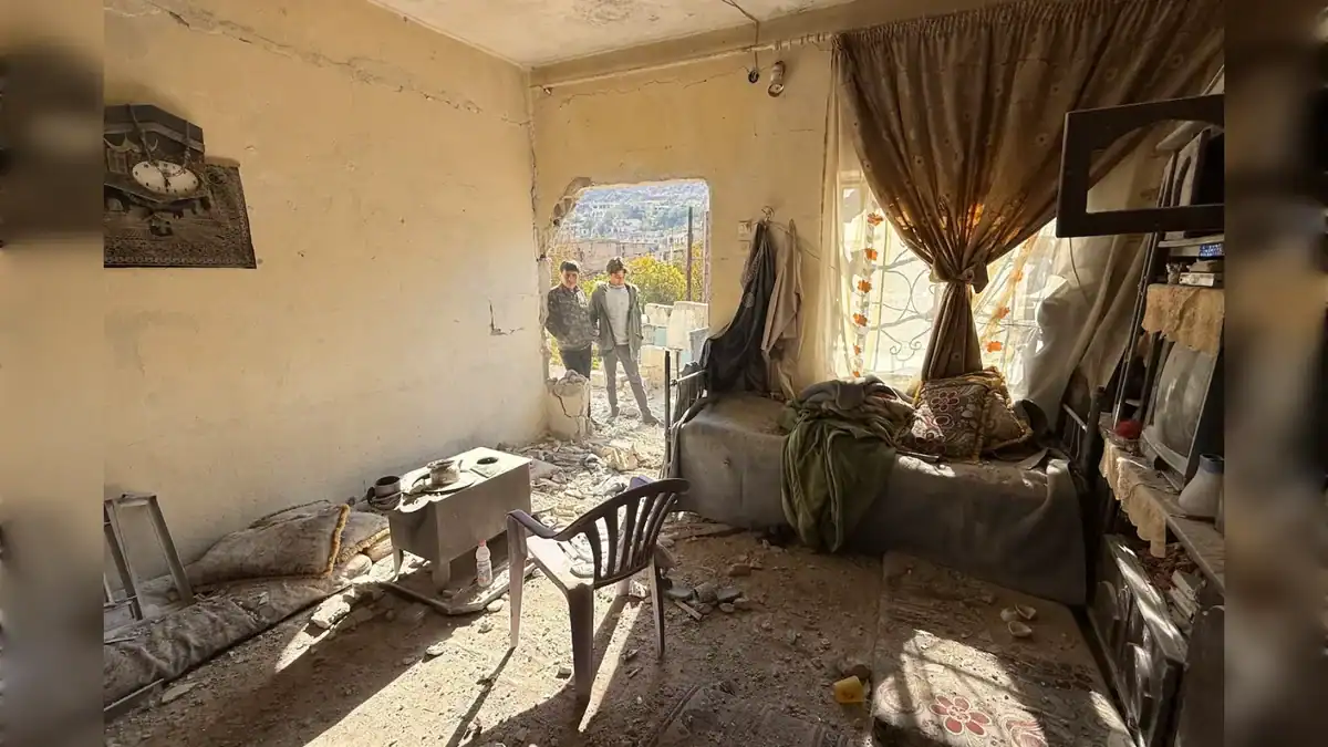 Interior of a damaged house in Beit Jinn, Syria, with two boys standing outside a hole in the wall
