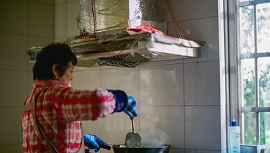 A representative image of a domestic worker cooking in a kitchen.