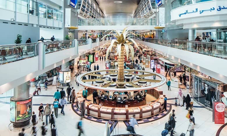Representative image showing travellers moving through a busy terminal at Dubai International Airport, with the golden palm at the centre of the duty-free area.