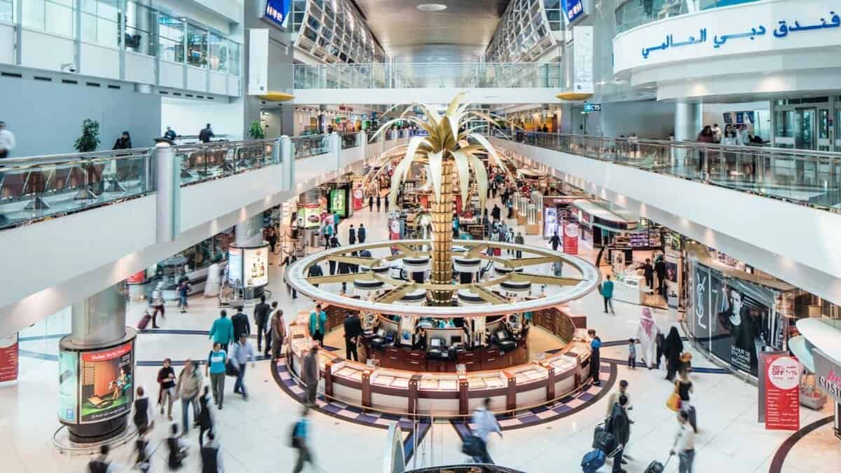 Representative image showing travellers moving through a busy terminal at Dubai International Airport, with the golden palm at the centre of the duty-free area.