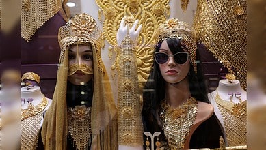 Gold jewellery displayed on mannequins in a Dubai shop window, featuring ornate headpieces and necklaces.