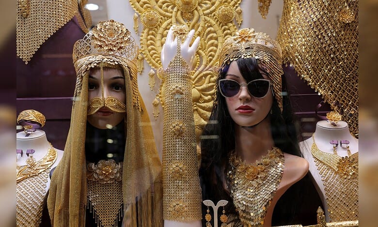 Gold jewellery displayed on mannequins in a Dubai shop window, featuring ornate headpieces and necklaces.
