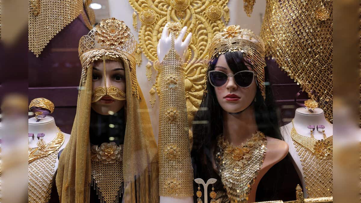 Gold jewellery displayed on mannequins in a Dubai shop window, featuring ornate headpieces and necklaces.