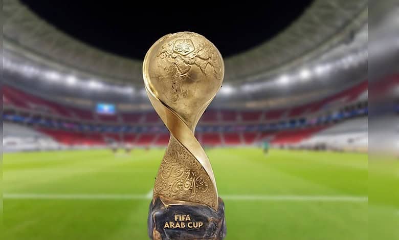 The FIFA Arab Cup trophy displayed on a football pitch inside a brightly lit stadium.