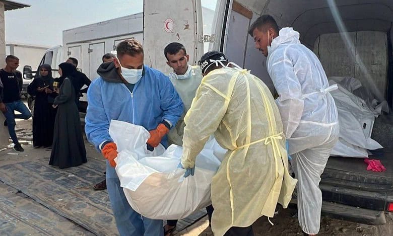 Health workers in protective suits carry a body bag from a vehicle after Israel handed over the bodies of Palestinians in Gaza.