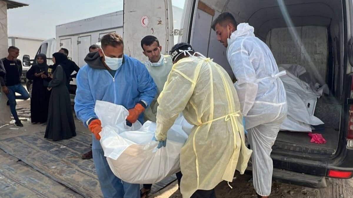 Health workers in protective suits carry a body bag from a vehicle after Israel handed over the bodies of Palestinians in Gaza.