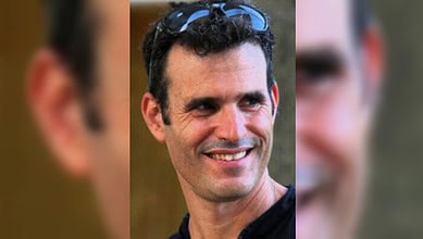 A smiling man with dark curly hair and sunglasses on his head, identified as Dror Or.