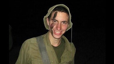 Israeli soldier Hadar Goldin smiling in uniform at night.