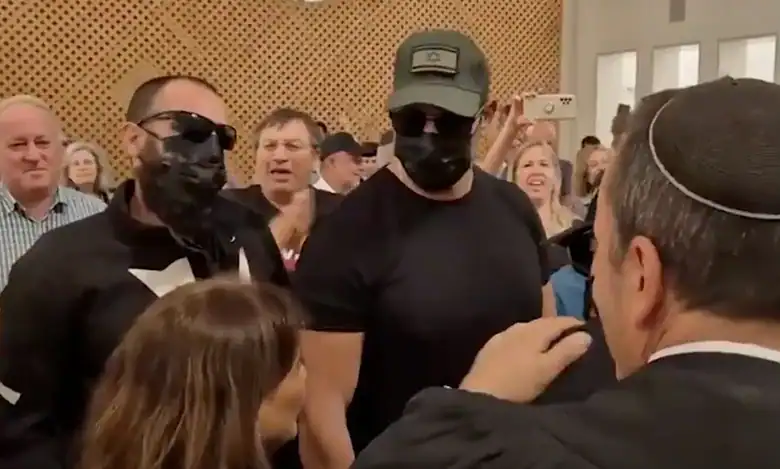 Masked Israeli soldiers accused of raping a Palestinian detainee stand in a Jerusalem courtroom as supporters applaud around them.